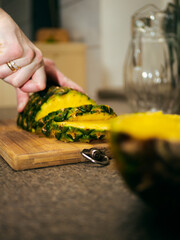 a woman cuts a pineapple on a wooden board with a knife. cooking a dish with pineapple. slicing pineapple on a chopping board. 
