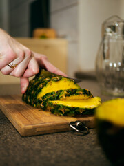 a woman cuts a pineapple on a wooden board with a knife. cooking a dish with pineapple. slicing pineapple on a chopping board. 