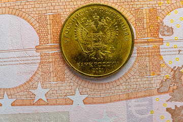 This image shows a 10 RUR coin over a euro banknote. It depicts the EU economy in crisis and recession due to sanctions against Russia. - 558183273