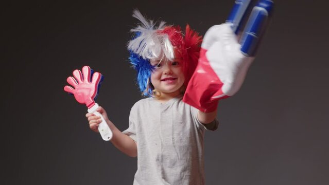 Young girl with a mohawk on his head in the color of the French flag supports his sports team. Football fan baby at the stadium rejoices at the victory of his team