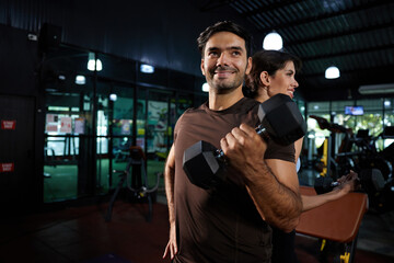 Fototapeta na wymiar young athletics smiling and lifting dumbbell in the gym