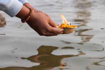 A devotee releasing the worship lamp/diya in the river Ganga - obrazy, fototapety, plakaty