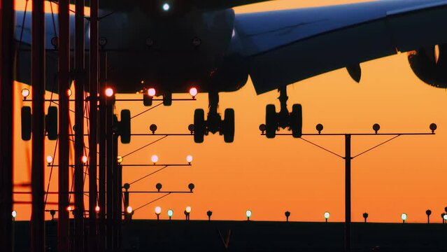 Plane landing in airport at sunset. Telephoto closeup, slow motion, 4K.