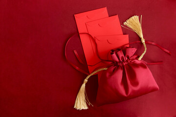 Chinese New Year, red silk pocket money bag with red envelope on red background, lucky item...