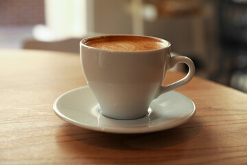 Cup of aromatic hot coffee on wooden table in cafe, closeup