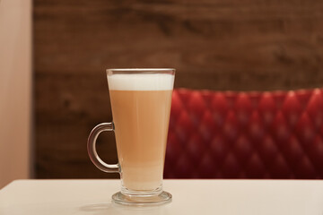 Glass with delicious coffee on beige table in cafe. Space for text