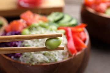 Closeup view of chopsticks with edamame bean against blurred background