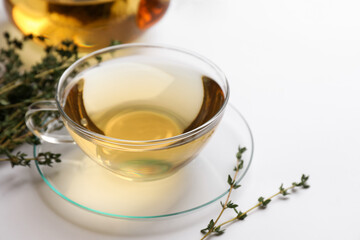 Cup of aromatic herbal tea with thyme on white table