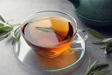 Cup of aromatic herbal tea with sage on grey table