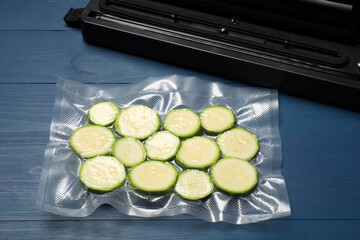 Sealer for vacuum packing and plastic bag with cut zucchinis on blue wooden table