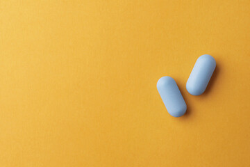 Pills and space for text on orange background, top view. Potency problem
