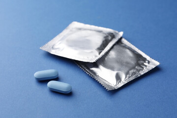 Pills and condoms on blue background. Potency problem