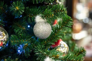 Christmas tree background and Christmas decorations in the mall. White silver balls on green fur. Happy New Year theme