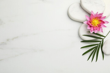 Flat lay composition with spa stones, lotus flower and leaf on white marble table. Space for text
