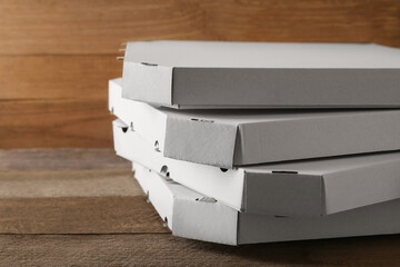Stack of empty pizza boxes on wooden table, closeup. Space for text