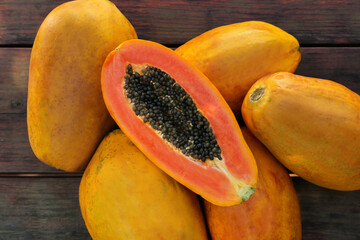 Fresh ripe cut and whole papaya fruits on wooden table, flat lay