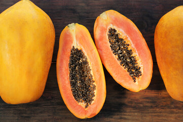 Fresh ripe cut and whole papaya fruits on wooden table, flat lay