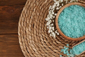 Bowl and spoon with sea salt, beautiful flowers on wooden table, flat lay. Space for text