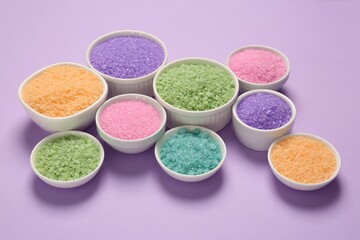 Fototapeta na wymiar Different types of aromatic sea salt on purple background