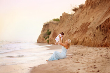 Mother and daughter having fun playing on the beach at sunset