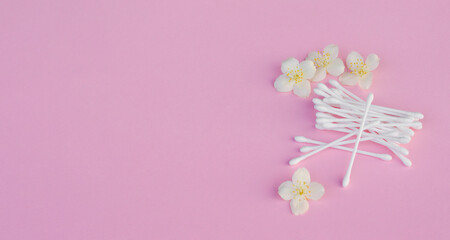 White buds near white jasmine flowers on light pink, close up. Skincare product for everyday beauty...