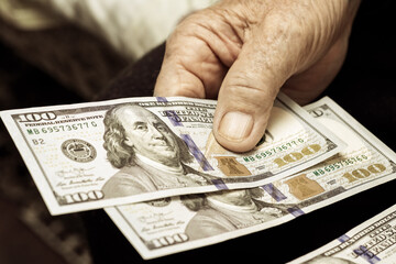 Grandfather holds money in his hands. An elderly man counts dollars
