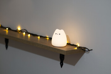 Cute cat shaped silicone night lamp standing on a wall shelf