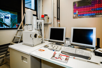 Workplace of a scanning desktop electron microscopy station and periodic table of chemical elements on the wall