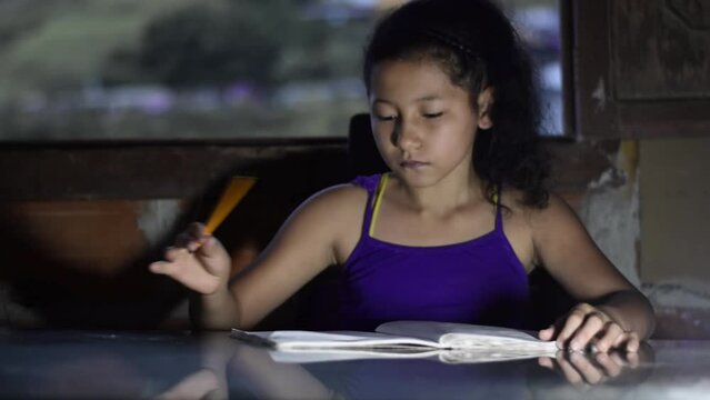 close-up of a brown-skinned latina girl, writing with her yellow pencil in her notebook. little girl studying at home.