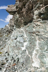Fototapeta na wymiar Pit face of abandonned asbestos surface mine, visible asbestos sinuosity, mix of chrysotile and tremolite, free fibers blowing with the wind, in natural environment, Queyras, French Alps
