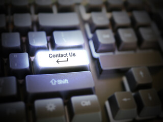 A glowing bright 'contact us' button, key, message on the keyboard. Customer service concept. Internet or online contact for services and businesses.