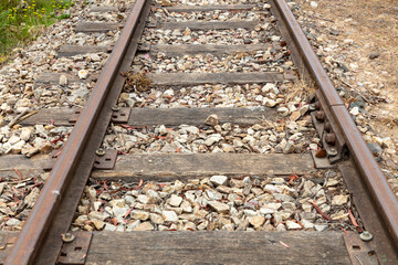 Photograph of old and rusty and out of service railway tracks with white stones and dead weeds