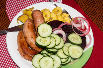 meal consisting of sausage and roasted banana with vegetable salad