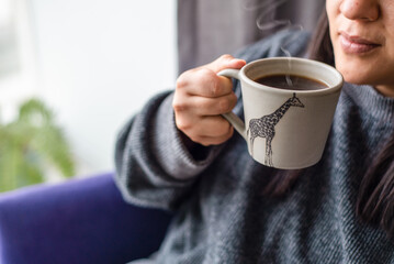 woman holding a coffee cup. Drinking using a giraffe mug