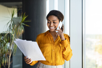 Corporate communication. Smiling african american female manager holding financial documents and...