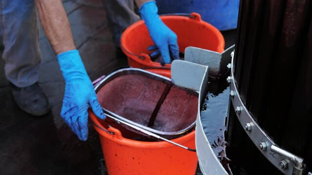 Close-up the wine is poured from the fermentation and fermentation tank into a bucket with a large sieve to filter out small particles.