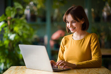 Young woman working on laptop while sitting at cafe