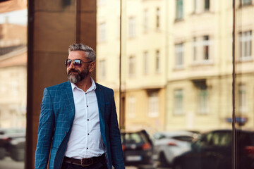 A senior businessman in a blue suit with a briefcase walking through the city