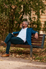 Obraz premium Modern senior businessman resting on a bench in the city on a break from work