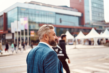 A senior businessman in a suit walking around the city after work