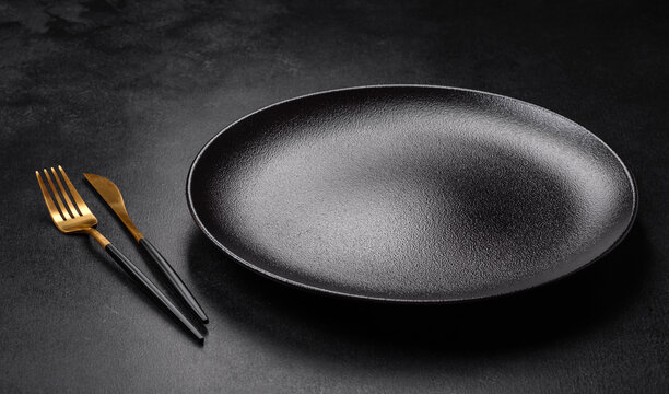 Empty beautiful black ceramic plate on a dark concrete background