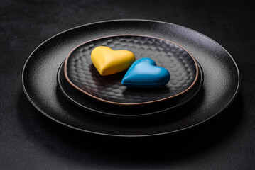 Chocolate hearts in the colors of the Ukrainian flag on a black ceramic plate