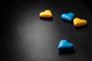 Chocolate hearts in the colors of the Ukrainian flag on a black ceramic plate