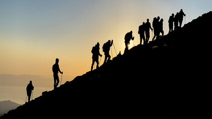 group of harmonious mountaineers hiking to the summit at sunrise