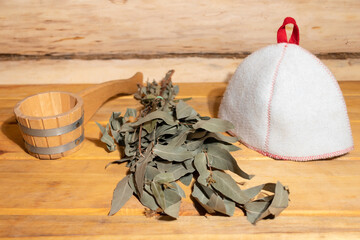 Sauna cap, wooden ladle and eucalyptus broom. The concept of an old Russian traditional bath