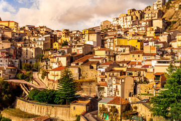 old mediterranean mountain dense town with levels of yellow houses and terraces on a mountain in evening light, vintage european village on a rock