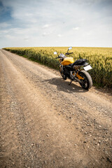 Gravel road with the motorcycle in to a wheat field