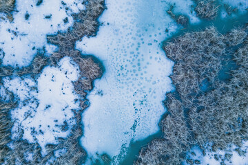 Panoramic aerial view of a frozen lake with animal tracks and cracked ice. Animal tracks on the frozen surface of the lake. Cracked ice on the lake