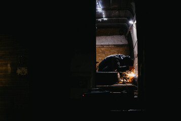 worker man in a welding mask welds metal in the back of a van