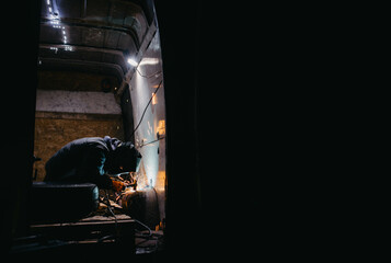 worker man in a welding mask welds metal in the back of a van